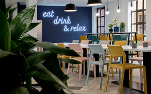 Nardi Thrill Stackable Monobloc Chair with Armrest in Different Finishes with Long Table in Cafeteria