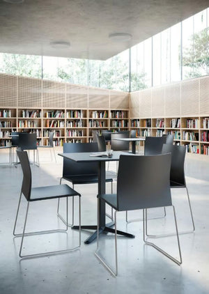 Artesia Stackable Chair With Table And Bookshelves In Library Setting