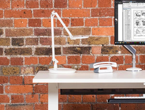 Humanscale Adjustable And Sustainable Element Disk Desk Light 8 On White Table With Brick Wall