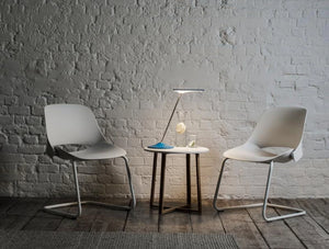 Humanscale Horizon 2 Adjustable Desk Light With Touch Dimming Feature In Blue On Side Table With White Chair