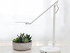 Humanscale Nova Adjustable Desk Light With Charging Desktop Base 2 In White With Small Plant On White Table