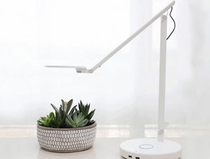 Humanscale Nova Adjustable Desk Light With Charging Desktop Base 2 In White With Small Plant On White Table