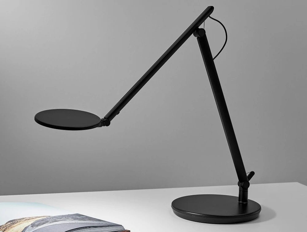 Humanscale Nova Adjustable Desk Light With Charging Desktop Base 4 In Black On White Table With Book
