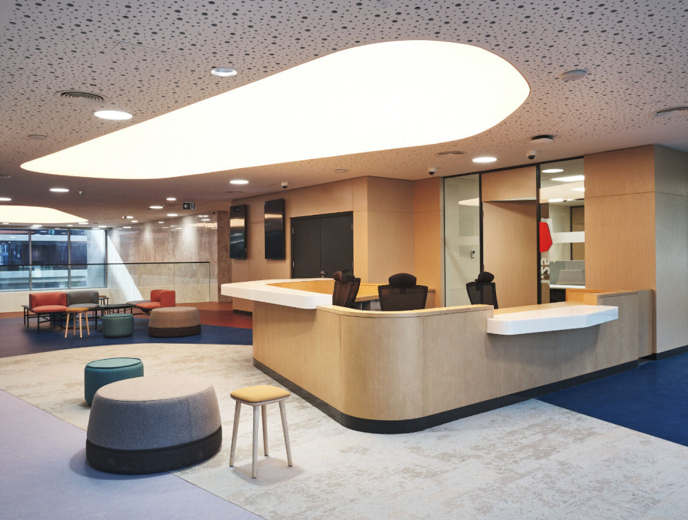 Light Oak Wooden Reception Counter Office Furniture With Upholstered Pouffe And Table In Reception Setting