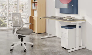 RoundE Bamboo Sit Stand Desk with White Pedestal and Grey Armchair in Modern Office Setting